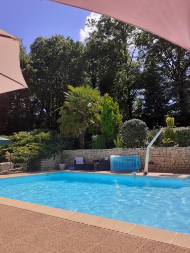 - une piscine dans une cour avec un parasol et des arbres dans l'établissement Gîtes du Bois de Bontemps, à Sarlat-la-Canéda
