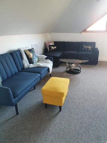 uma sala de estar com um sofá azul e um banco amarelo em Mount Bolton Apartment em Portlaw