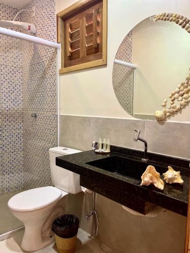 a bathroom with a sink and a toilet and a mirror at Pousada Ventos do Norte in Barra Grande