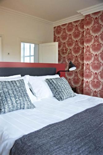 a bed with two pillows and a red wall at Villa Adélaïde in Chimay