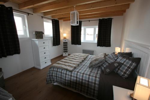 a bedroom with a bed and two windows at Les Authentics - Le Domaine d'Autrefois & Spa in Bolsenheim
