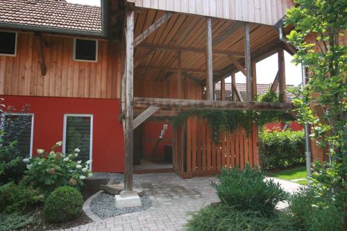 a large wooden building with a red wall at Les Authentics - Le Domaine d'Autrefois & Spa in Bolsenheim