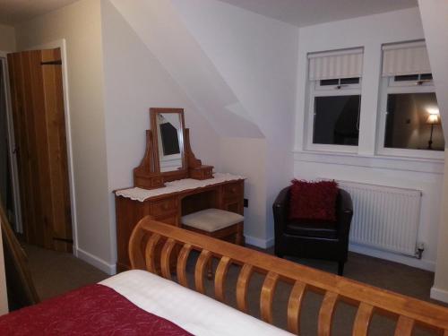 a bedroom with a bed and a mirror and a chair at Station House Lanark Bed and Breakfast in Lanark