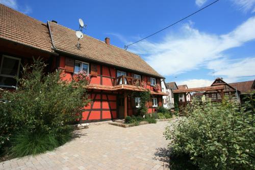 a red house with a brick courtyard in front of it at Les Authentics - Le Domaine d'Autrefois & Spa in Bolsenheim