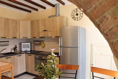 einen Kühlschrank aus Edelstahl in einer Küche mit Holzschränken in der Unterkunft SoleLuna in San Quirico dʼOrcia