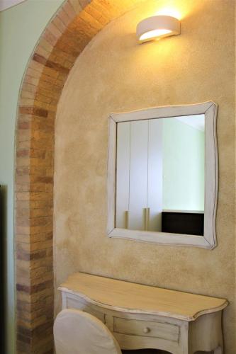a mirror on a wall with a table and a stool at SoleLuna in San Quirico dʼOrcia