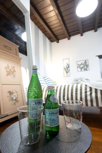 two green bottles and two glasses on a table at Lo Schiaccianoci Bed&Breakfast de Charme in Scanzorosciate
