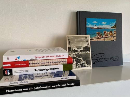 a stack of books sitting on a shelf with a picture at Strandblick mit Strandkorb & Fahrrädern in Glücksburg