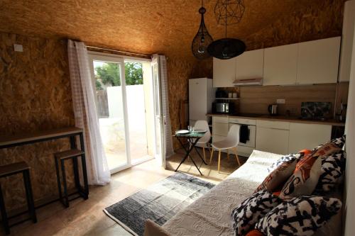 a living room with a couch and a kitchen with a window at Les Bastidons de l'Isle - Le Saumane - 3 étoiles in L'Isle-sur-la-Sorgue