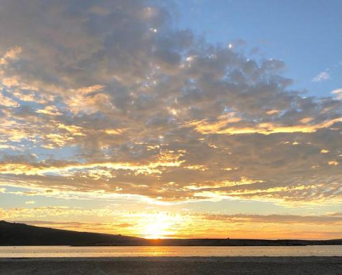 einen Sonnenuntergang über einem Wasserkörper mit Wolken in der Unterkunft Views at 69 B&B in Langebaan