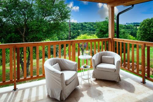 two chairs and a table on a deck with a view at Ferienhaus mit privaten Schwimmteich und Sauna in Oed bei Gleisdorf