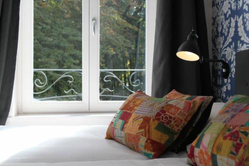 a bed with a window and two pillows and a lamp at Villa Adélaïde in Chimay