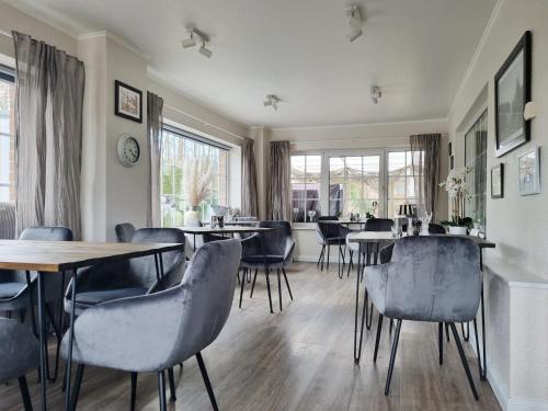 a dining room with tables and chairs and windows at Hotel-Pension Am Fuchsberg in Bad Doberan
