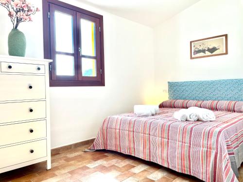 a bedroom with a bed and a dresser with towels at Le Corti Sarde Apartments in Bari Sardo