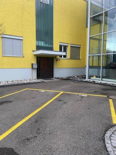 an empty parking lot in front of a yellow building at Geräumige Wohnung im Schweizer Vekehrspunkt in Hunzenschwil