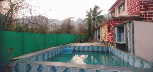 GhātgharWeekend Villa at Nature's Lap (Malshej Ghat)的一座带绿色围栏的房屋旁的游泳池