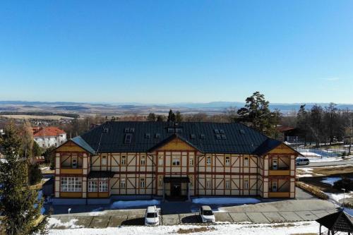 a large building with a black roof in the snow at Apartmán Srnka s výhľadom na Vysoké Tatry in Smokovce