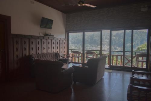 a living room with chairs and a balcony with windows at Heaven Seven Kandy in Kandy