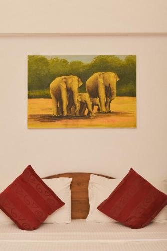 a painting of three elephants on a wall above a bed at Heaven Seven Kandy in Kandy