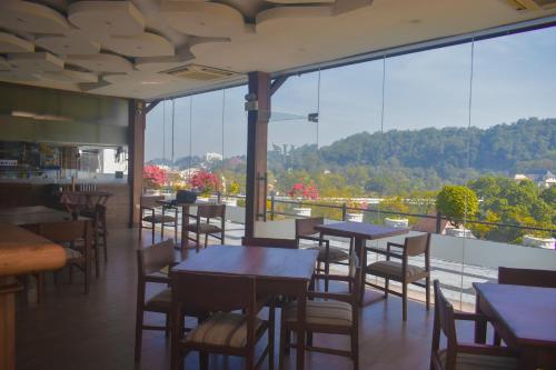 a restaurant with tables and chairs and a large window at Heaven Seven Kandy in Kandy