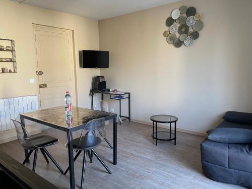 ein Wohnzimmer mit einem Tisch, Stühlen und einem Sofa in der Unterkunft Appartement 42 m2 à Vittel proche Thermes-SPA in Vittel