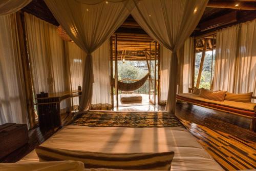a bedroom with a bed in a room with curtains at Sharma Springs 5 bds Luxurious Bamboo Mansion Pool in Bringkit