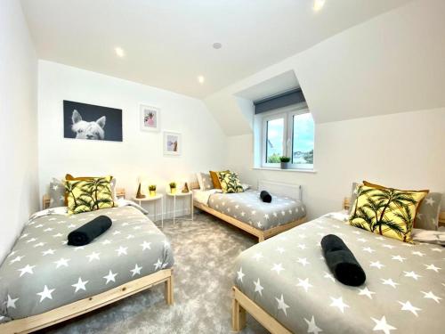 a bedroom with two beds and a couch in it at NEW Beautiful Large 3 bedroom House - 5 Minutes to the nearest Beach! - Great Location - Garden - Parking - Fast WiFi - Smart TV - Newly decorated - sleeps up to 7! Close to Poole & Bournemouth & Sandbanks in Lytchett Minster