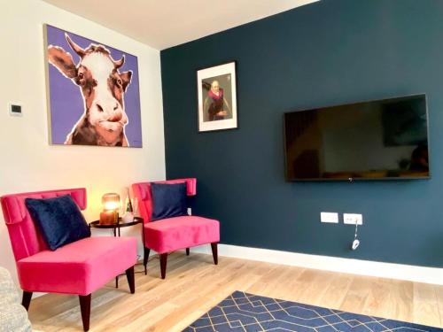 a room with two chairs and a tv with a cow on the wall at NEW Beautiful Large 3 bedroom House - 5 Minutes to the nearest Beach! - Great Location - Garden - Parking - Fast WiFi - Smart TV - Newly decorated - sleeps up to 7! Close to Poole & Bournemouth & Sandbanks in Lytchett Minster