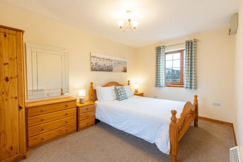 een slaapkamer met een bed, een dressoir en een raam bij Carnedd Cottage in Dwyran