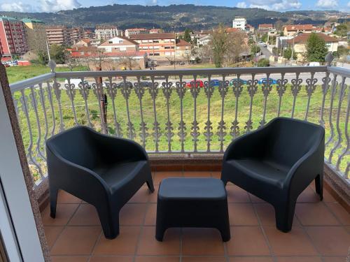two chairs and a stool on a balcony with a view at Apartamentos Sanjuan in Porriño
