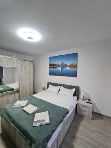 a bedroom with a large bed with a green blanket at Smart Apartament in Braşov