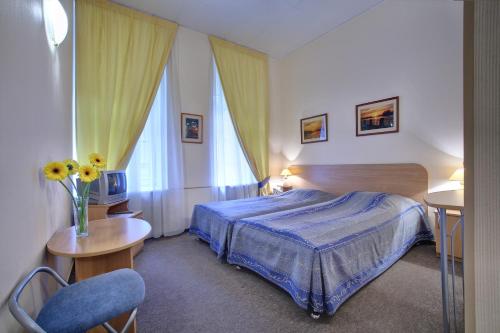 1 dormitorio con 1 cama y un jarrón de flores en Rinaldi at Petrogradskaya Side, en San Petersburgo