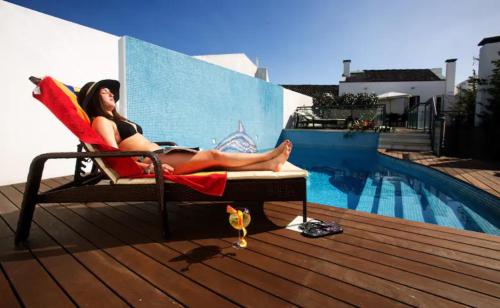a woman sitting in a chair next to a pool at 2Stay - A2 in Ponta Delgada