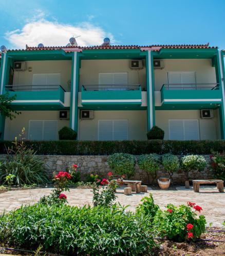 a building with blue columns and flowers in a courtyard at ΑΚΤΗ ΞΟΒΡΙΟΣ in Kivérion