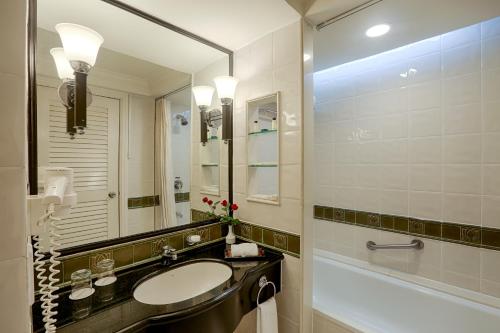 a bathroom with a sink and a tub and a mirror at PARKROYAL Yangon in Yangon