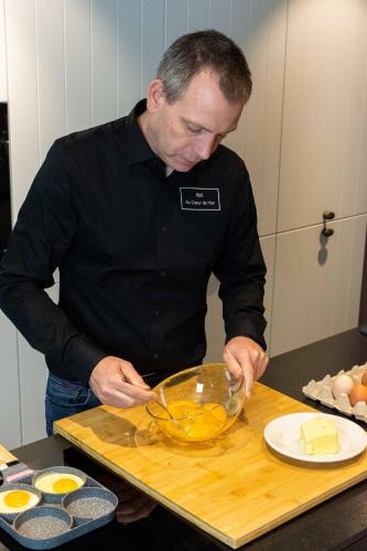 a man standing in a kitchen preparing food in a bowl at B&B Au Cœur de Han in Han-sur-Lesse
