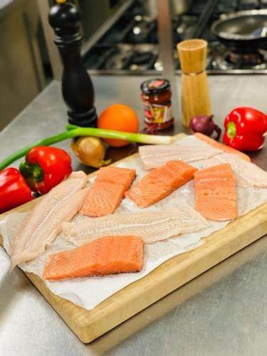 a cutting board with fish and vegetables on a counter at Gasthaus Dernedde in Osterode