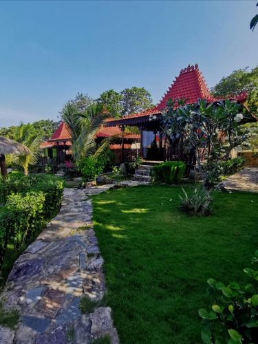 a pathway leading to a house with a grass yard at Mirabelle Joglo Village in Karimunjawa
