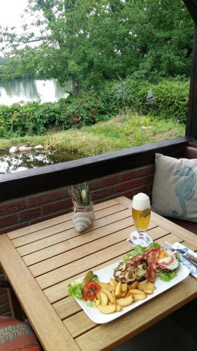 a table with a plate of food and a glass of beer at Hotel Seelust in Hennstedt