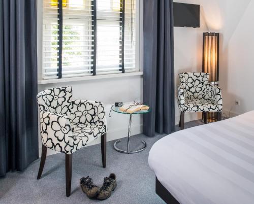 a bedroom with a bed and two chairs and a table at Gasterij Posthuys in Leerdam