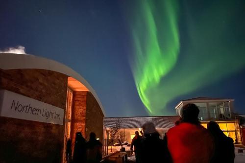 people standing outside a building watching the northern lights at Northern Light Inn in Grindavík