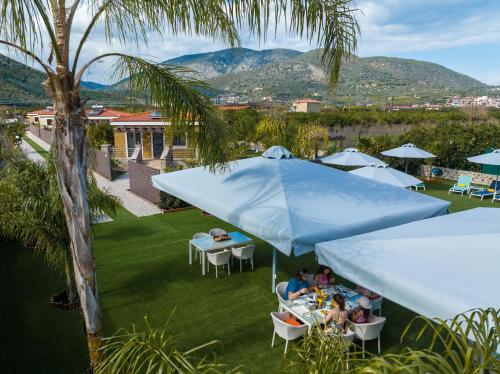 a group of people sitting at tables under a blue umbrella at Desa Green Homes in Ancient Epidavros
