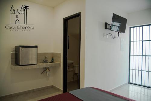 Habitación con puerta que da a un baño con microondas. en Casa Chenera, en Campeche