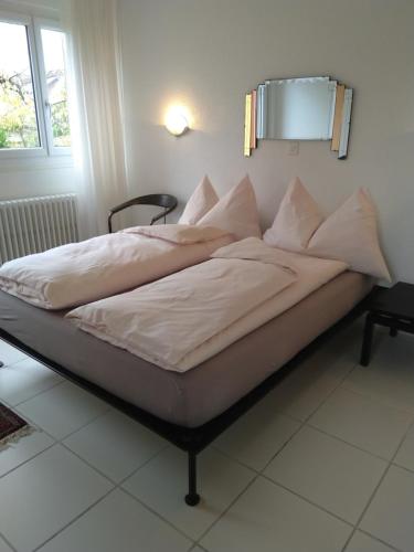 a bed with white sheets and pillows in a room at Swiss Borzoi House in Bellerive