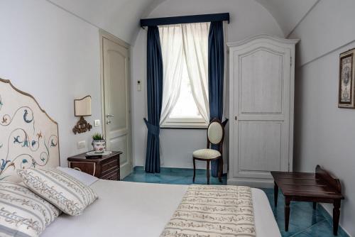 a bedroom with a bed and a desk and a window at Villa San Cosma in Ravello