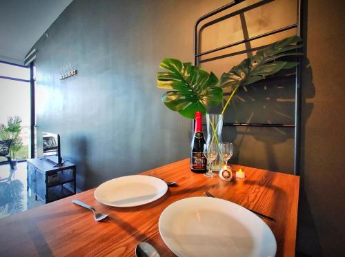 a wooden table with two plates and a bottle and a plant at Beacon Executive Suite at Georgetown for 10pax and 2 BED ROOM in George Town