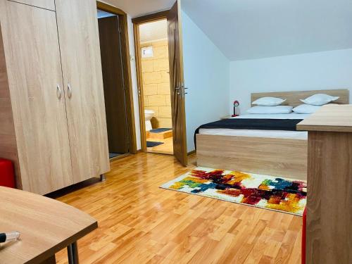 a bedroom with a bed and a rug on a wooden floor at Casa Adriana in Băile Herculane