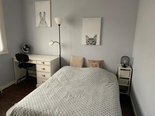a bedroom with a bed and a desk and two pictures at Maison chaleureuse avec cheminée et extérieur in Luxeuil-les-Bains