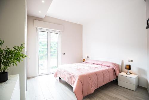 a white bedroom with a pink bed and a window at CDO Apartment in Capo dʼOrlando
