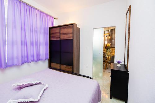 a bedroom with a bed and a purple window at Glicinia in Šibenik